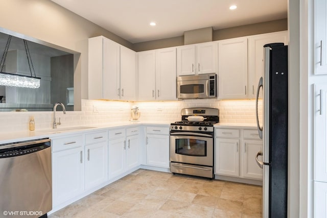 kitchen featuring decorative backsplash, appliances with stainless steel finishes, white cabinets, and a sink