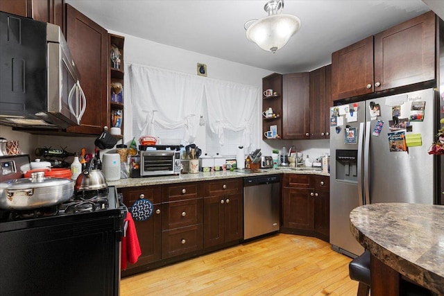 kitchen with open shelves, stainless steel appliances, a sink, dark brown cabinetry, and light wood-type flooring