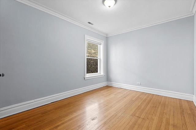 empty room with baseboards, visible vents, light wood-style flooring, and crown molding