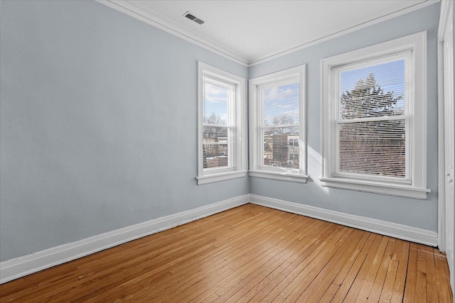 empty room with baseboards, light wood-style flooring, visible vents, and crown molding