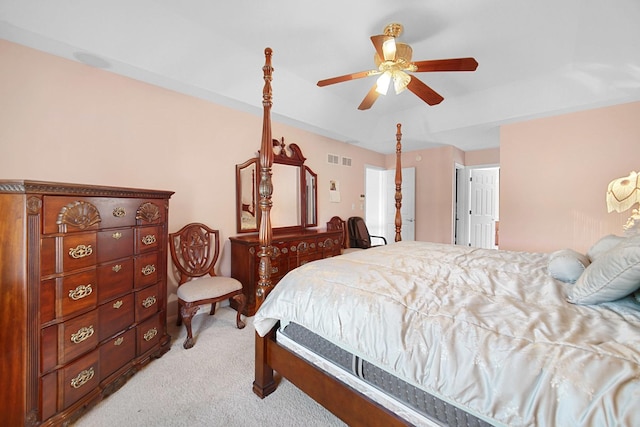 bedroom featuring light carpet, a tray ceiling, visible vents, and a ceiling fan