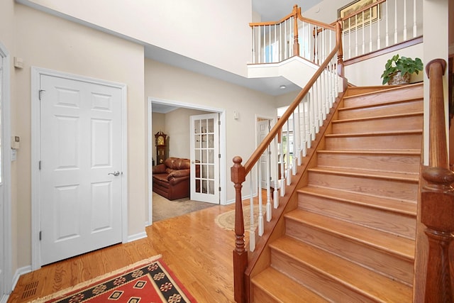 entryway with wood finished floors, baseboards, french doors, and stairs