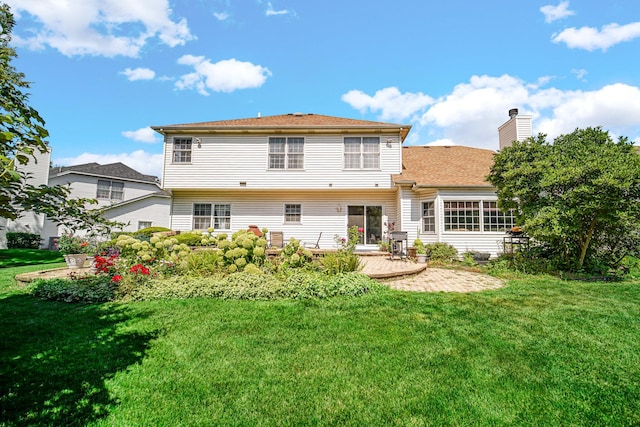 back of property featuring a chimney, a patio, and a yard