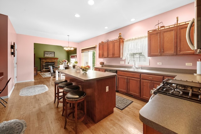 kitchen with light wood finished floors, brown cabinetry, a breakfast bar, a center island, and a sink