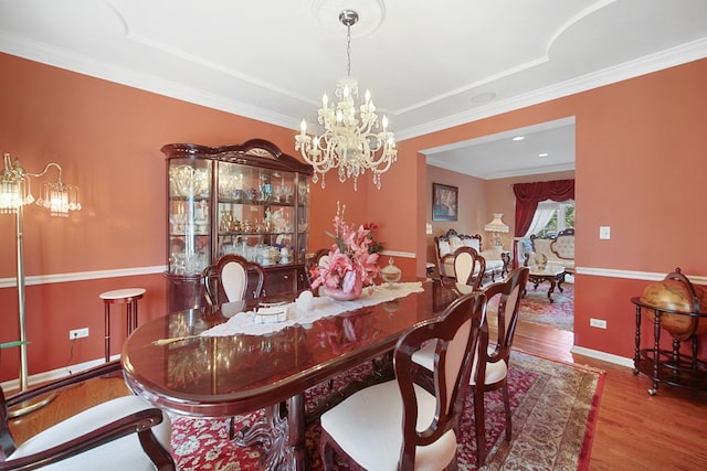 dining space featuring baseboards, a chandelier, wood finished floors, and ornamental molding