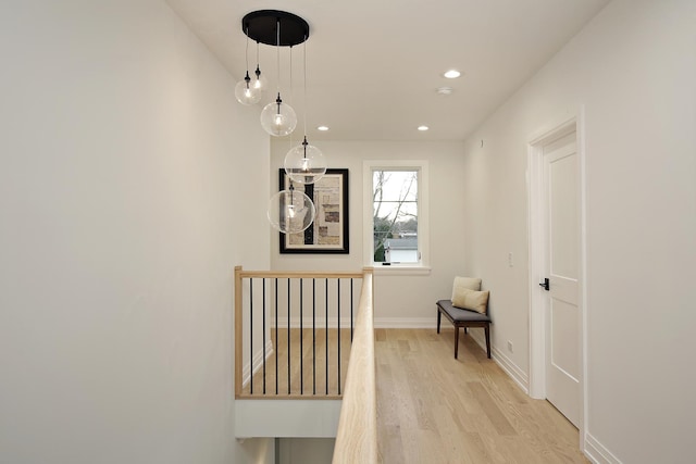 corridor with recessed lighting, baseboards, light wood-style flooring, and an upstairs landing