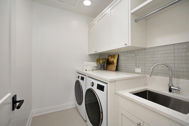 clothes washing area featuring light tile patterned floors, separate washer and dryer, a sink, baseboards, and cabinet space