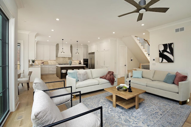 living room featuring ornamental molding, recessed lighting, visible vents, and light wood-style floors