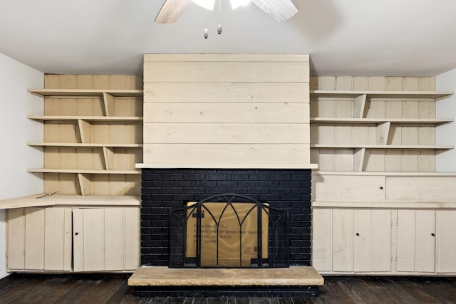 room details featuring a ceiling fan, a brick fireplace, and wood finished floors