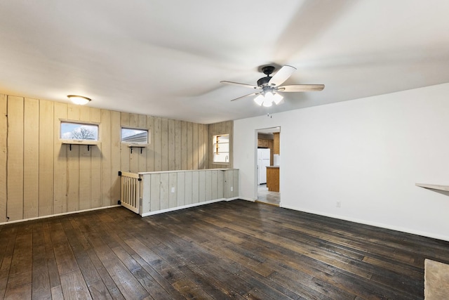 unfurnished living room with hardwood / wood-style floors, a ceiling fan, and baseboards