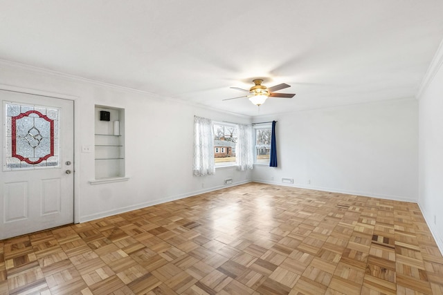 spare room featuring visible vents, built in features, crown molding, baseboards, and ceiling fan