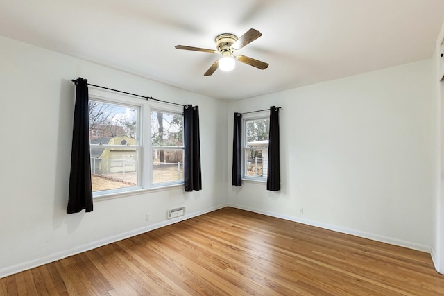 empty room with baseboards, ceiling fan, and light wood finished floors