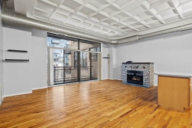 unfurnished living room with light wood-style floors, a fireplace, baseboards, and coffered ceiling