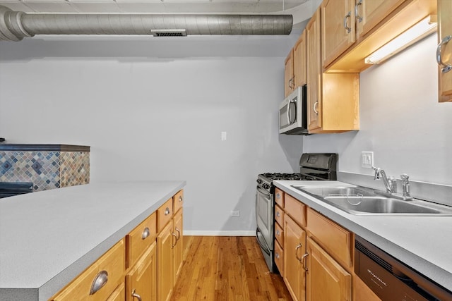 kitchen with a sink, visible vents, light countertops, appliances with stainless steel finishes, and light wood-type flooring