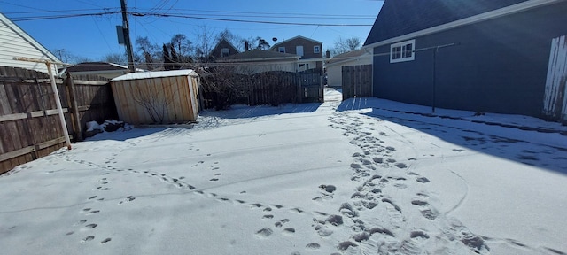 yard layered in snow with fence, an outdoor structure, and a shed