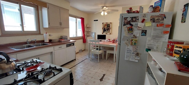 kitchen with light floors, white cabinetry, a sink, ceiling fan, and white appliances