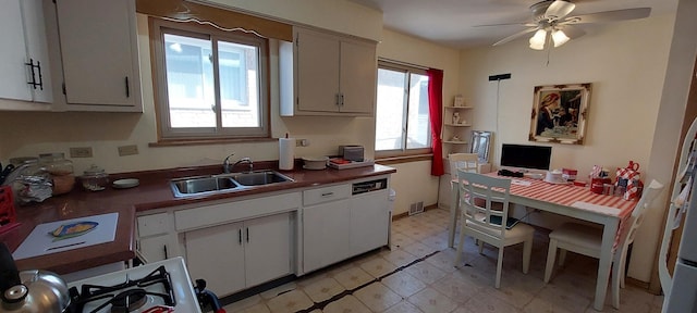 kitchen with white cabinets, dark countertops, ceiling fan, light floors, and a sink