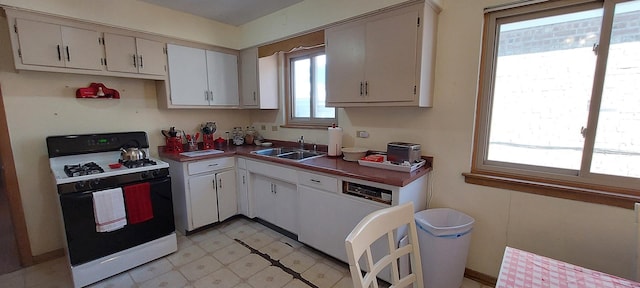 kitchen featuring range with gas stovetop, light floors, white cabinetry, white dishwasher, and a sink