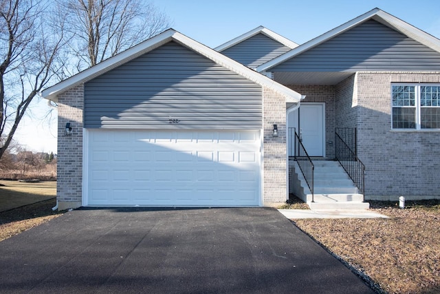 ranch-style home with a garage, aphalt driveway, and brick siding