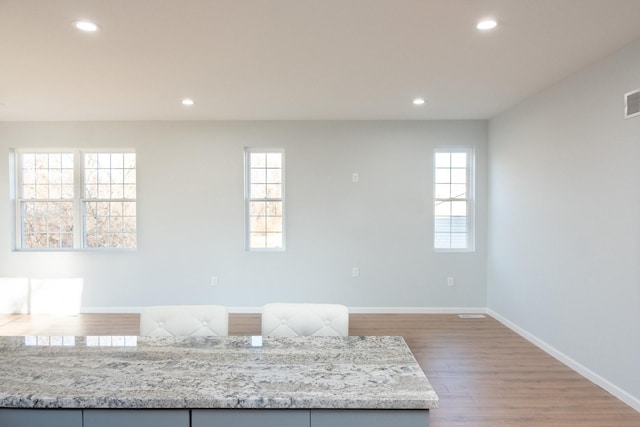 kitchen featuring light stone countertops, baseboards, wood finished floors, and recessed lighting