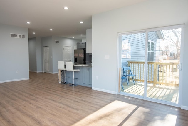 unfurnished living room featuring baseboards, visible vents, wood finished floors, and recessed lighting