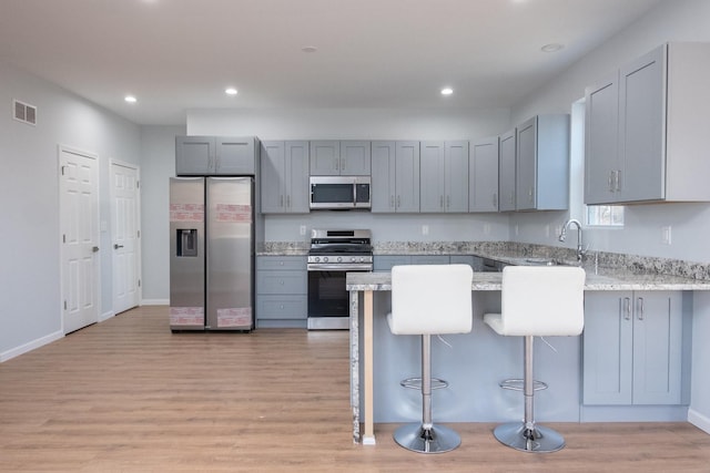 kitchen with stainless steel appliances, visible vents, a peninsula, and gray cabinetry