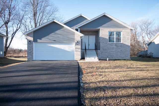 view of front of home featuring an attached garage, a front yard, aphalt driveway, and brick siding