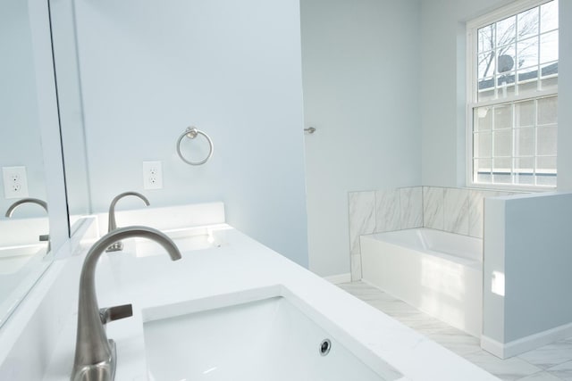 bathroom featuring marble finish floor, a garden tub, a sink, and double vanity