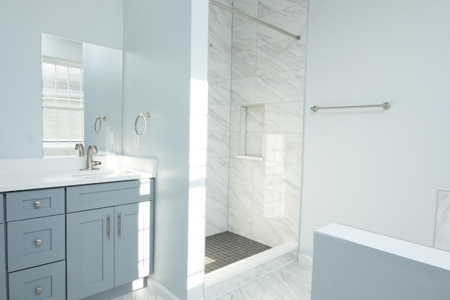 full bathroom featuring marble finish floor, a tile shower, and vanity