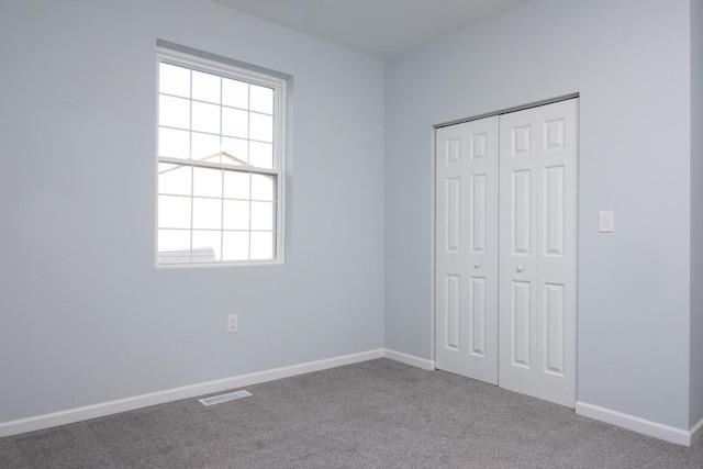 unfurnished bedroom with carpet, a closet, visible vents, and baseboards