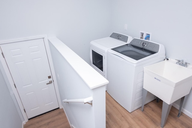 laundry area featuring laundry area, light wood-style flooring, separate washer and dryer, and a sink