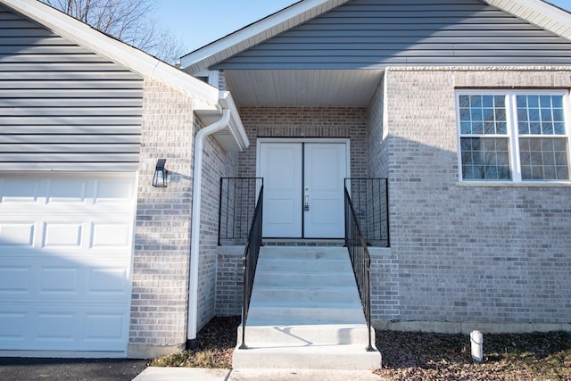 entrance to property featuring a garage and brick siding