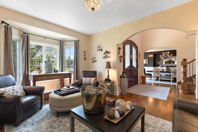 living area with arched walkways, wood finished floors, and a chandelier