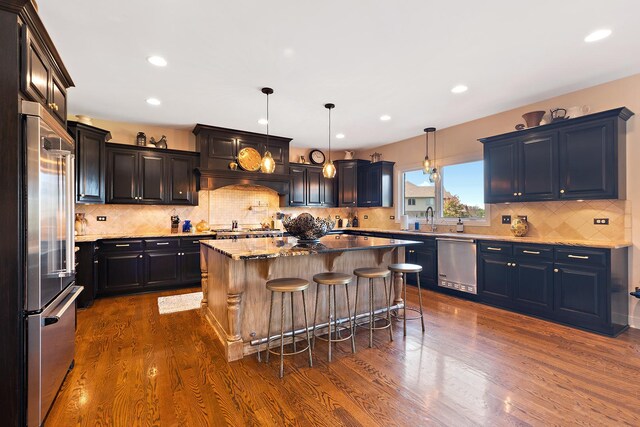 kitchen featuring dark wood-style floors, a kitchen island, appliances with stainless steel finishes, and a sink