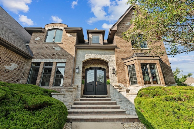 view of exterior entry with french doors and brick siding