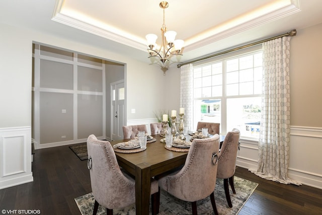 dining room with dark wood finished floors, a raised ceiling, a notable chandelier, and a decorative wall