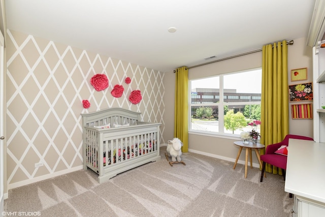 bedroom featuring visible vents, an accent wall, carpet flooring, baseboards, and wallpapered walls