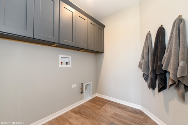 laundry area featuring cabinet space, baseboards, hookup for a gas dryer, light wood-style flooring, and washer hookup