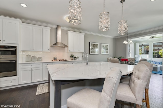 kitchen with dark wood-type flooring, wall chimney exhaust hood, stainless steel appliances, and crown molding