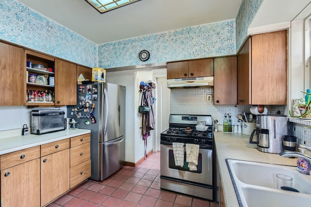 kitchen with appliances with stainless steel finishes, light countertops, a sink, and under cabinet range hood