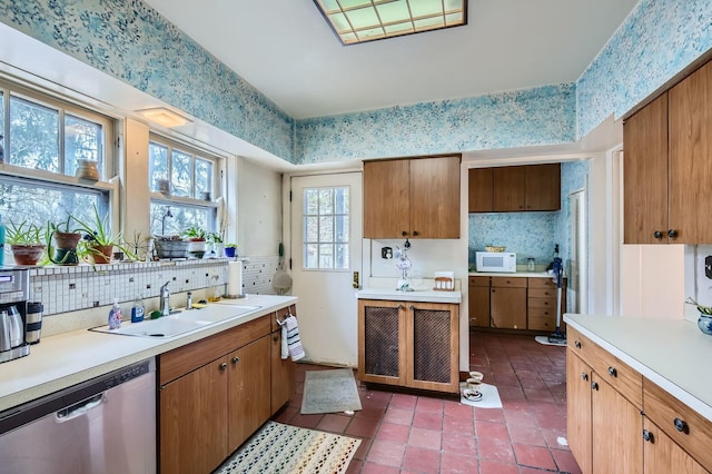 kitchen with white microwave, a sink, light countertops, dishwasher, and tasteful backsplash