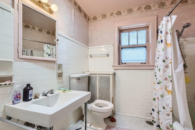 bathroom featuring a sink, curtained shower, toilet, and tile walls