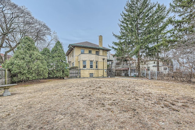 rear view of house featuring a chimney, fence, and brick siding