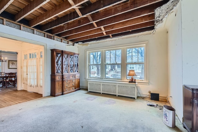 miscellaneous room with radiator heating unit, a chandelier, and carpet flooring