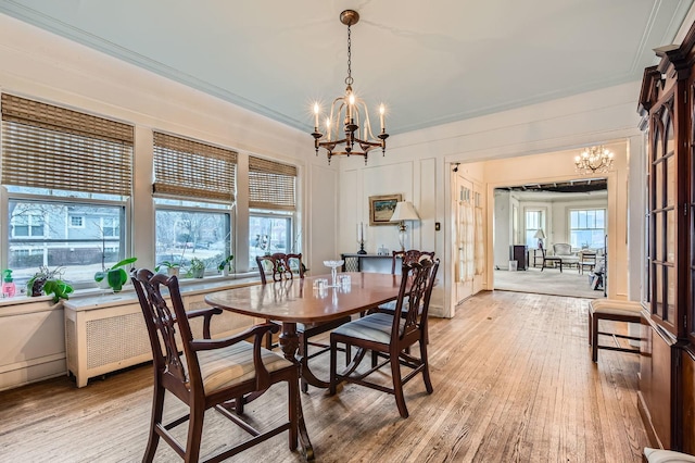 dining area with a chandelier, light wood-type flooring, and ornamental molding