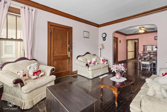 living room with baseboards, arched walkways, ceiling fan, ornamental molding, and dark wood-type flooring