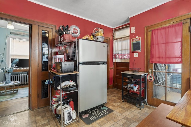 kitchen with radiator heating unit, crown molding, and freestanding refrigerator