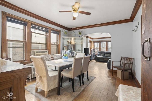 dining space featuring hardwood / wood-style flooring, arched walkways, and crown molding