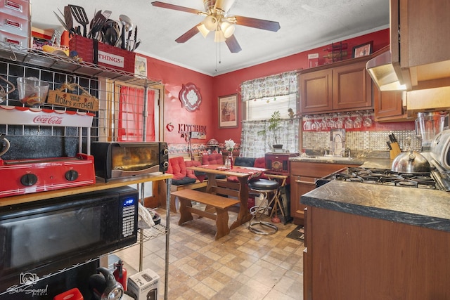 kitchen with backsplash, brown cabinetry, ceiling fan, a sink, and black microwave