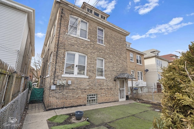 back of house featuring brick siding, a yard, and a fenced backyard